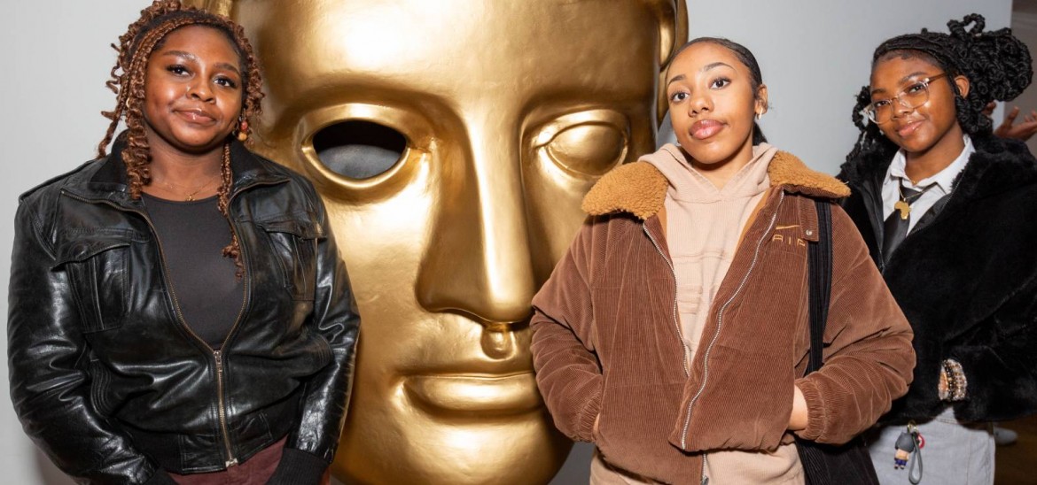 Three girls pose with BAFTA statuette.